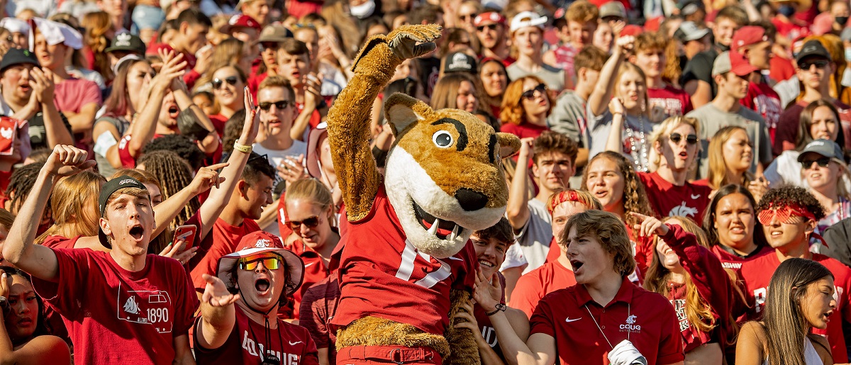 A crowd of students at a football game, with Butch T. Cougar in front